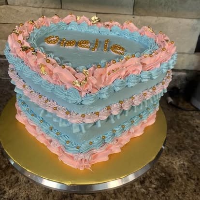 Pastel en forma de corazón color azul con decoración rosa estilo vintage y perlas doradas.